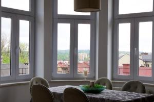 a dining room with a table and chairs and windows at Apartament Ratuszowy in Cieszyn