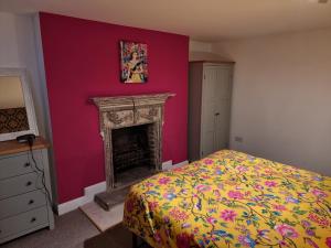 a bedroom with a pink wall with a fireplace at Entire Ground Floor Flat, Free Off-Street Parking and Large Garden in London