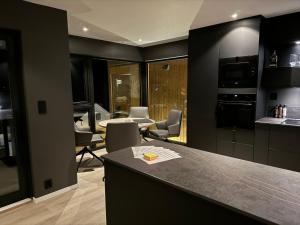 una cocina con paredes negras y una barra con sillas en Moderne topp leilighet, 