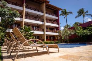 een resort met 2 stoelen naast een zwembad bij Apartamento de Charme no Cumbuco - Condomínio Jardim Reale in Caucaia