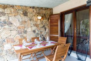 una mesa de madera con sillas y una pared de piedra. en Francy Family Sea Apartment, en Limpiddu