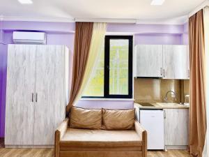 eine Küche mit lila Wänden und ein Sofa vor dem Fenster in der Unterkunft Khidikari Hotel in Ambrolauri