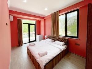 a bedroom with a large bed with red walls at Khidikari Hotel in Ambrolauri