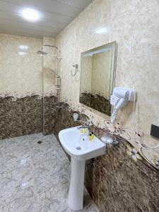a bathroom with a sink and a shower and a mirror at Khidikari Hotel in Ambrolauri