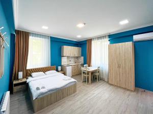 Schlafzimmer mit blauen Wänden, einem Bett und einem Schreibtisch in der Unterkunft Khidikari Hotel in Ambrolauri