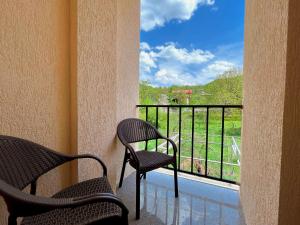 2 Stühle auf einem Balkon mit Blick auf ein Fenster in der Unterkunft Khidikari Hotel in Ambrolauri