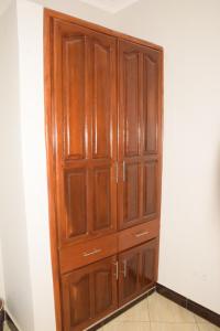 un armario de madera en la esquina de una habitación en Beatrice James airbnb Moshi en Moshi