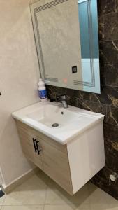 bagno con lavandino bianco e specchio di Appartement karakcho a Berkane