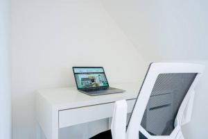 un computer portatile seduto sopra una scrivania bianca di Wavendon Retreat - Sleeps 6 - Free Parking, Fast Wifi and Smart TV by YOKO PROPERTY a Milton Keynes