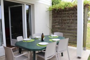 uma mesa com cadeiras brancas e uma garrafa de vinho em Le 501 F2 de plain-pied avec terrasse em Courseulles-sur-Mer