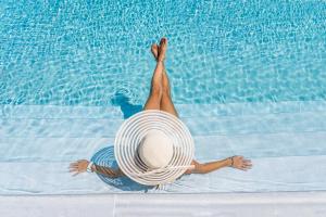 kobieta w kapeluszu leżąca w basenie w obiekcie Naxos Cave Suites w mieście Stelida