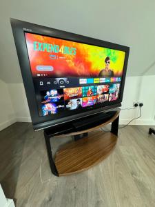 a flat screen tv sitting on top of a wooden stand at Gorgeous Loft Room in Beckenham