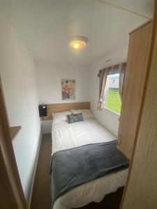 ein kleines Bett in einem kleinen Zimmer mit Fenster in der Unterkunft 15 Maple Rise in Gristhorpe