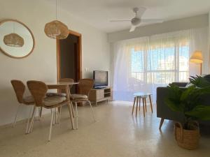 sala de estar con mesa, sillas y TV en Apartamento con piscina en Playa de Gandía en Playa de Gandia
