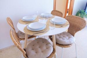 una mesa blanca con sillas y platos. en Apartamento con piscina en Playa de Gandía en Playa de Gandia