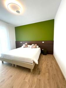 ein Schlafzimmer mit einem weißen Bett und einer grünen Wand in der Unterkunft LA ROSA DEL SILE in Quarto dʼAltino