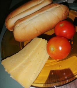 a plate with a hot dog and cheese and tomatoes at شقة الولاء Loyalty apartment in Dumyāţ al Jadīdah