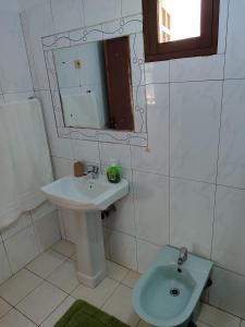 uma casa de banho branca com um lavatório e um espelho em Myni's House em Xai-Xai