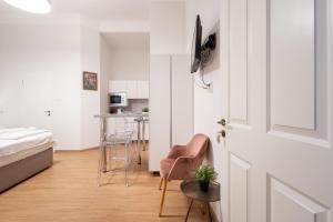 a bedroom with a bed and a door with a chair at Klauzál Garden City Apartments- studio K32 in Budapest