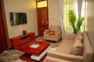a living room with a couch and a tv at Villa Home Apartment Dodoma in Dodoma
