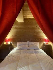 a bedroom with a bed with red curtains and two lamps at Chalet Savoyard vue panoramique in Jarrier