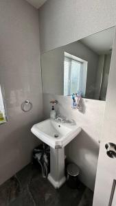 a bathroom with a white sink and a mirror at Luxury Home with Gym/Outdoor play area - 40 mins from Luton/Stansted in Knebworth