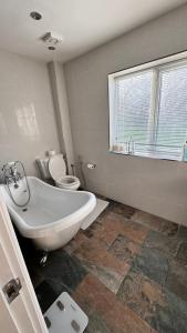 a bathroom with a tub and a toilet and a window at Luxury Home with Gym/Outdoor play area - 40 mins from Luton/Stansted in Knebworth