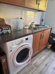 a washing machine in a kitchen with a sink at Luxury Home with Gym/Outdoor play area - 40 mins from Luton/Stansted in Knebworth