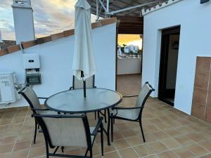 Casa Topacio Luxury Villa, 3 bedrooms sleeps 8 في ميخاس: طاولة وكراسي على شرفة مع مظلة
