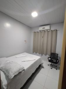 1 dormitorio blanco con 1 cama y 1 silla en Temporada de Hidro, piscina e casa privativas - Estadia memorável ou Evento, e pode check-in flexível 15h à madrugada, en Sorriso