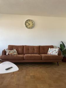 ein braunes Sofa im Wohnzimmer mit einer Uhr an der Wand in der Unterkunft Ferienwohnung Wilusa 2 in Rheinfelden