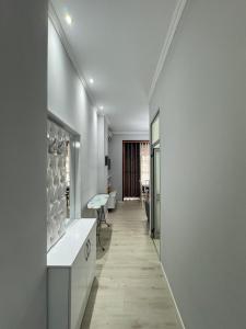 um corredor com paredes brancas e um longo corredor com uma mesa em Solei Apartments em Saranda