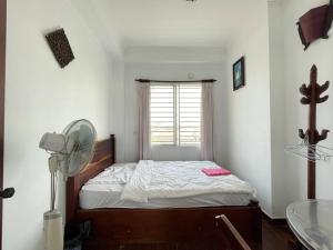 a bedroom with a bed with a fan and a window at Combretrata in Phnom Penh