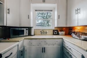 a kitchen with white cabinets and a microwave at 2BR 3BDs Historical TREE HOUSE on UT Campus in Austin
