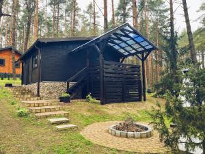 a black cabin with a roof and stairs in a forest at Domek obity dechami in Hartowiec