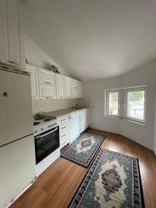 a kitchen with white appliances and a wooden floor at Deni house in Prizren