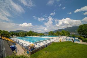 a large swimming pool in a park with mountains in the background at la Casa del Patio in Iseo