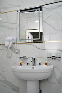 La salle de bains blanche est pourvue d'un lavabo et d'un miroir. dans l'établissement Next Hotel Samarkand, à Samarcande