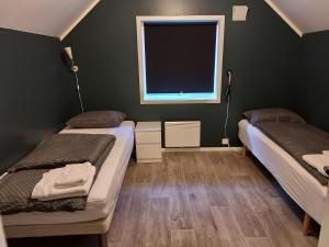two beds in a room with a window at Sentrumsnær overnatting in Alta