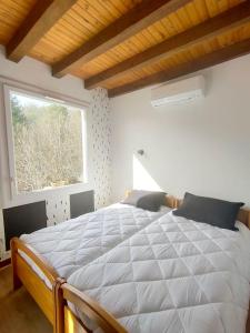 a bedroom with a large white bed with a window at A l' orée des bois, maison avec étang in Saint-Sylvestre