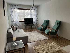- un salon avec un canapé, des chaises et une télévision dans l'établissement Apartment Tehtaankatu, à Kokkola