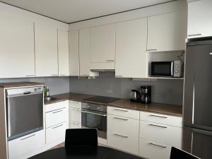 Una cocina con gabinetes blancos y electrodomésticos de acero inoxidable. en Apartment Tehtaankatu, en Kokkola