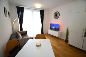 - un salon avec une table et un canapé dans l'établissement Flataid Apartments Stadion & Messe Graz, à Graz