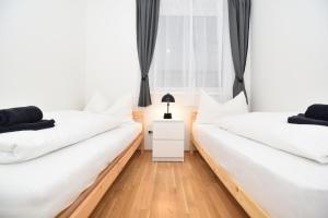 two beds in a room with white walls and wooden floors at Flataid Apartments Stadion & Messe Graz in Graz