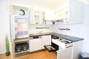  La cuisine est équipée de placards blancs et d'un réfrigérateur. dans l'établissement Flataid Apartments Stadion & Messe Graz, à Graz