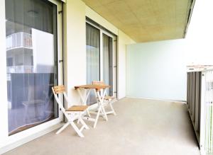 a balcony with two chairs and a table at Flataid Apartments Stadion & Messe Graz in Graz