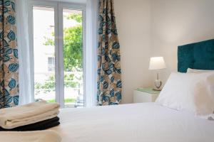 um quarto com uma cama branca e uma janela em Mónaco Nest em Ponta Delgada
