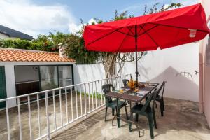 a table with a red umbrella on a balcony at Mónaco Nest in Ponta Delgada