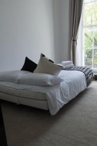 a bed with pillows on it in a room with a window at 1 bedroom apartment - The Onyx in Cheltenham