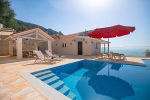 a house with a swimming pool with a red umbrella at Villa TheView in Katávolos